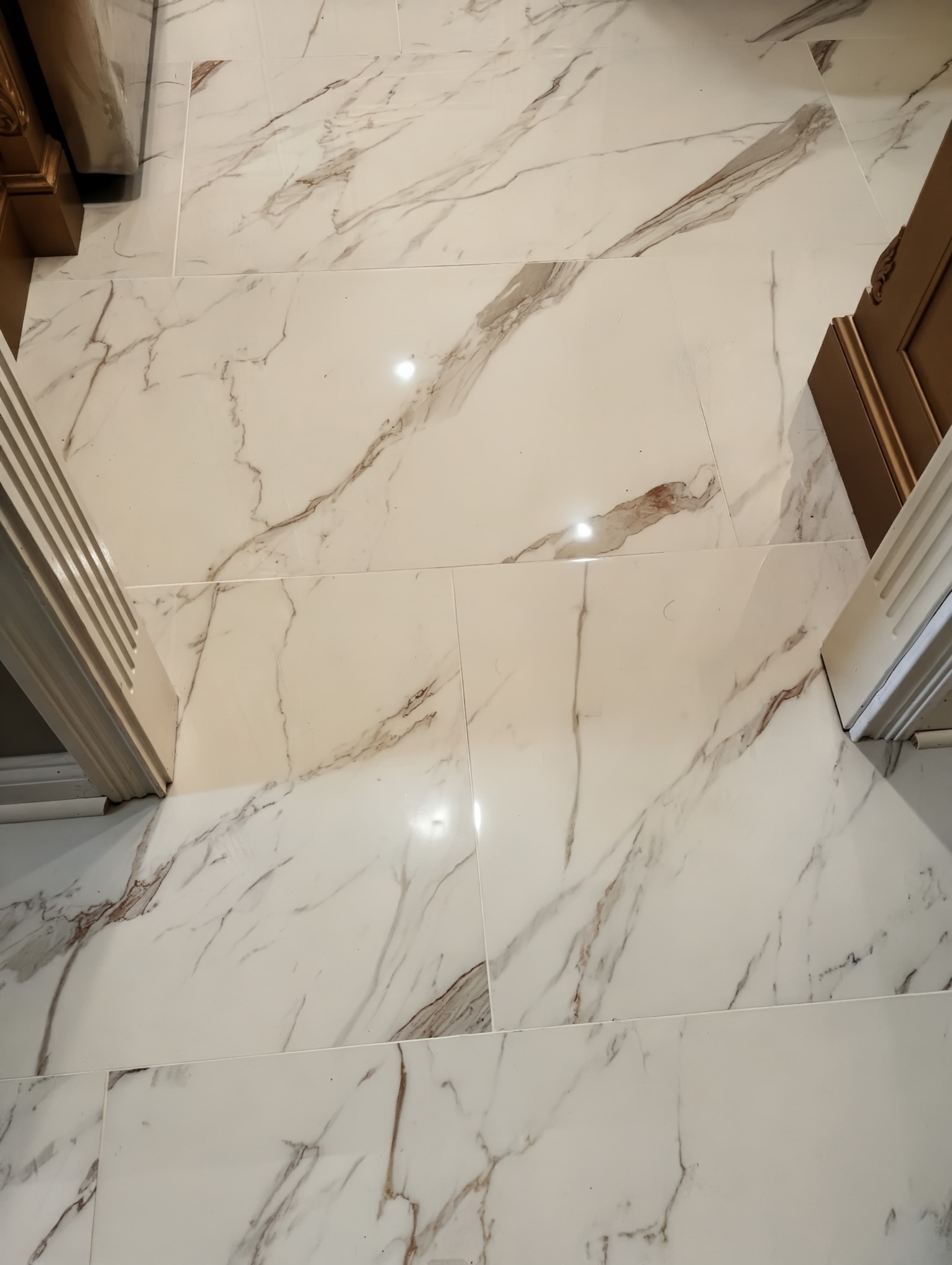 Large-format polished marble-look porcelain tile flooring in a bright interior.