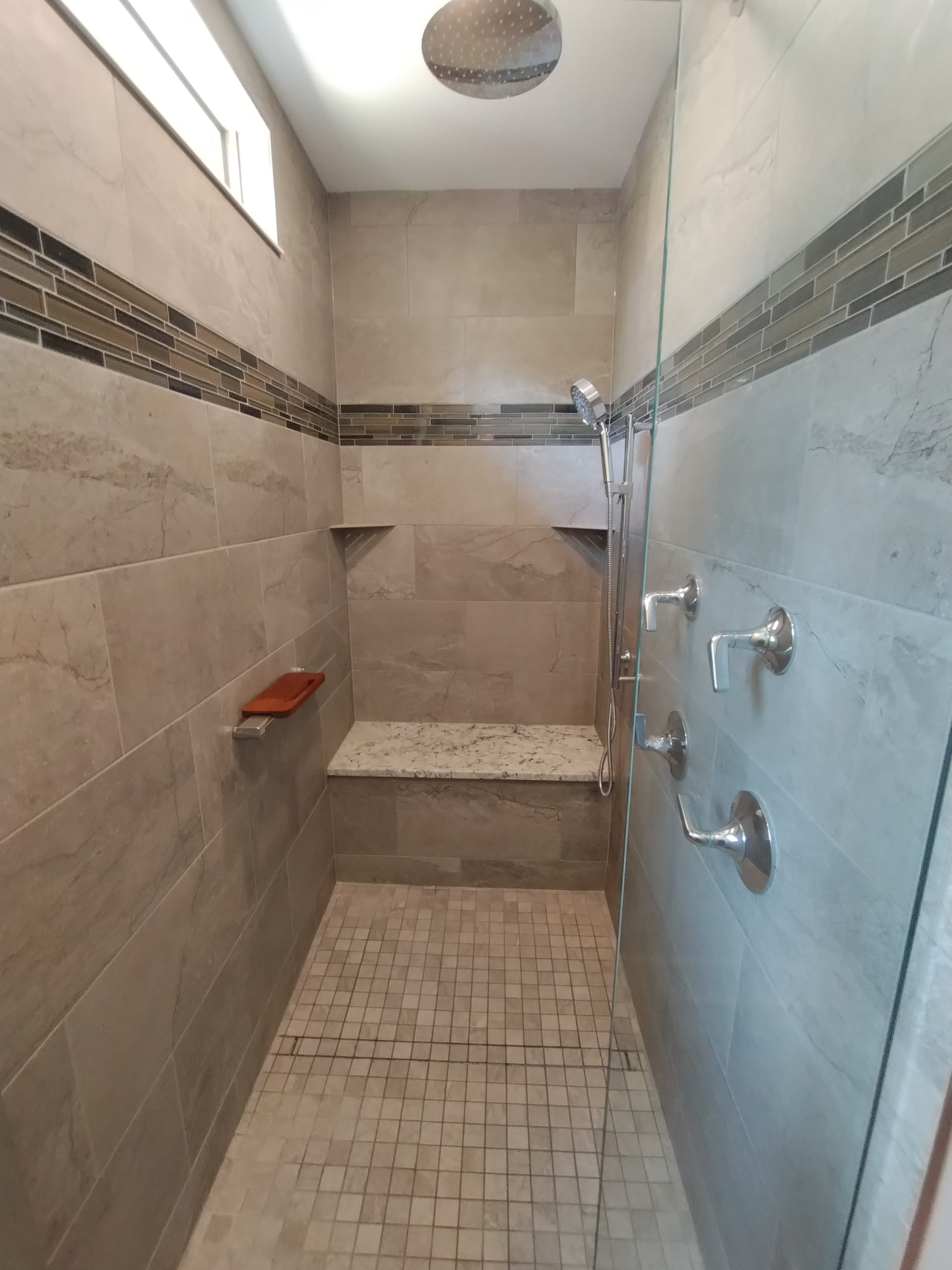 Classic beige shower with glass accent tile and granite bench
